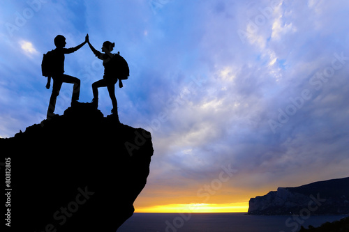 Silhouette of two people man girl success on the mountain