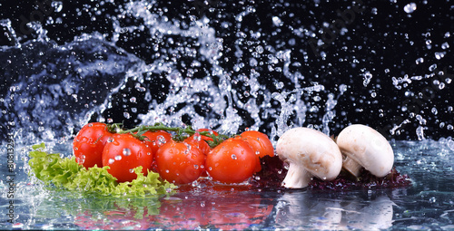 Red tomato, mushrooms and salad with water drop splash