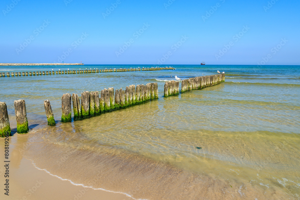 Fototapeta premium Wooden breakwater on beach in Ustka town, Baltic Sea, Poland