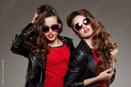 Sisters twins in hipster sun glasses laughing Two fashion models