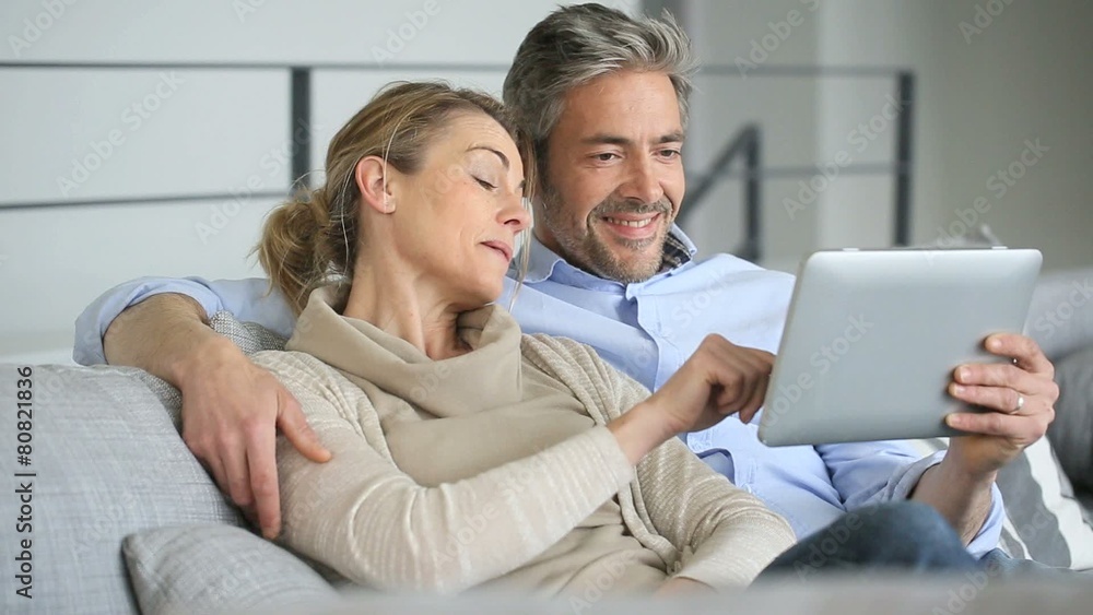 Mature couple relaxing in sofa and using digital tablet Mature couple relaxing in sofa and using digital tablet