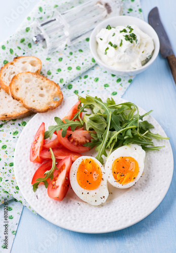 Breakfast with soft-boiled egg, arugula and tomatoes