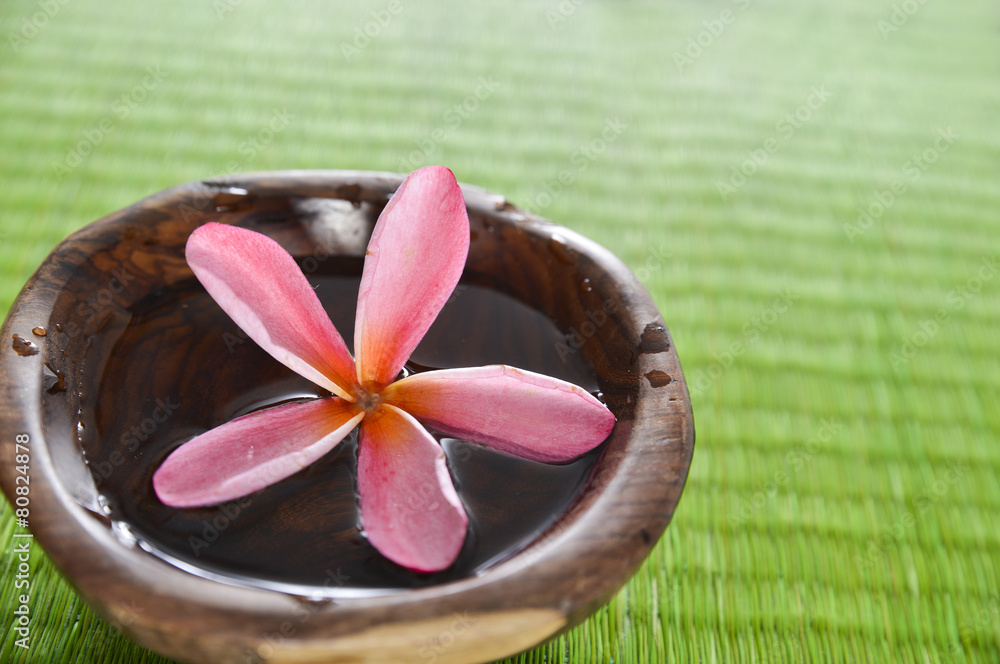 Red frangipani flower in wooden bowl on straw mat Red frangipani flower in wooden bowl on straw mat