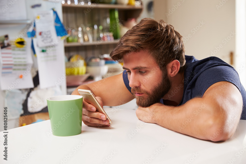 Young Man Drinking Coffee And Using Mobile Phone At Home Young Man Drinking Coffee And Using Mobile Phone At Home