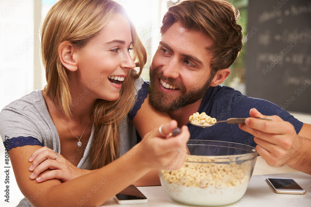 Young Couple Eating Breakfast In Kitchen Together Young Couple Eating Breakfast In Kitchen Together