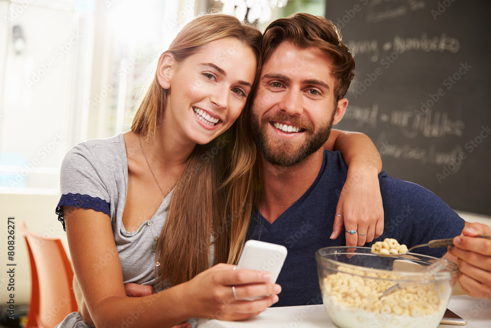 Young Couple Eating Breakfast Whilst Using Mobile Phones Young Couple Eating Breakfast Whilst Using Mobile Phones