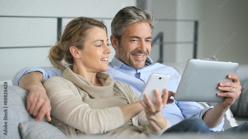 Mature couple at home using tablet and smartphone Mature couple at home using tablet and smartphone