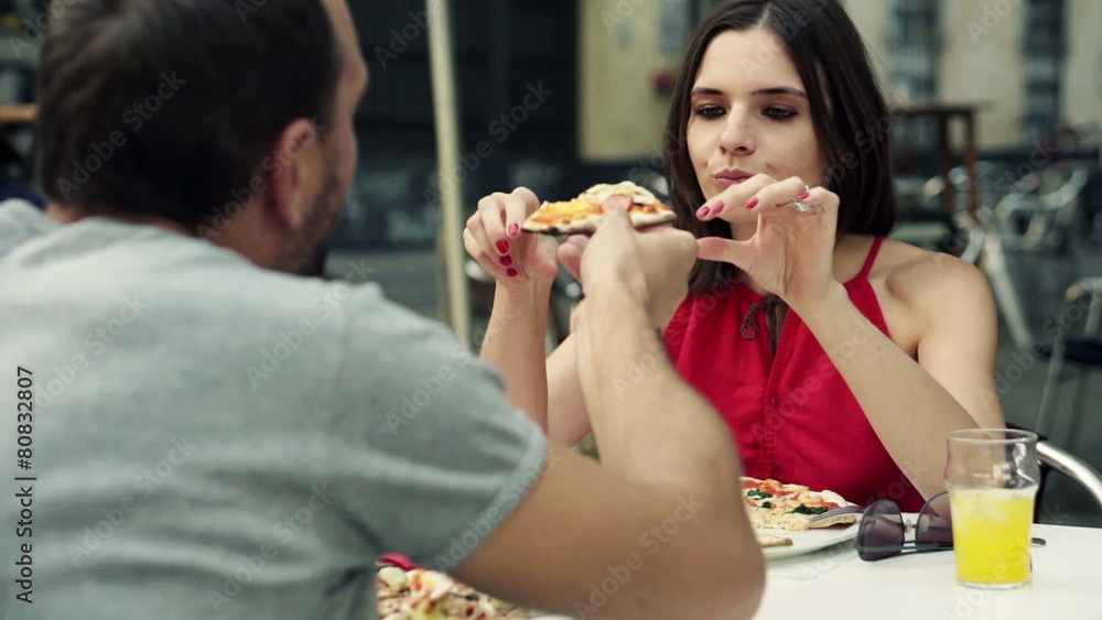 Couple eating and sharing pizza in cafe in the city Couple eating and sharing pizza in cafe in the city