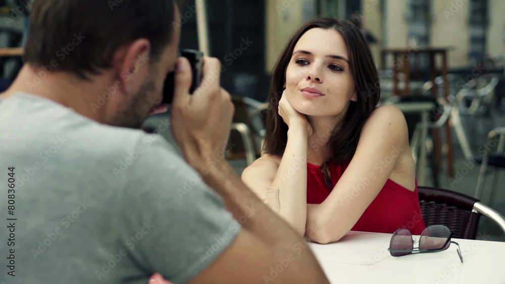 Man taking photo of his girlfriend with retro camera in cafe Man taking photo of his girlfriend with retro camera in cafe