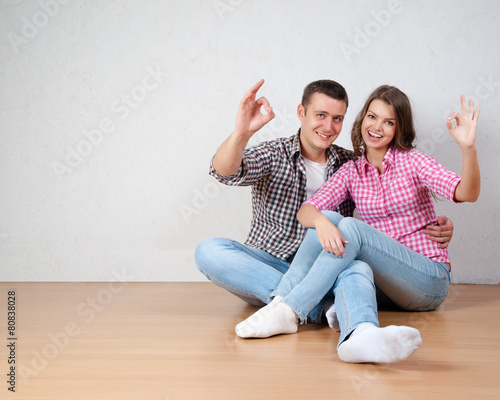 Portrait Of Happy Young Couple Sitting On Floor Looking Up 