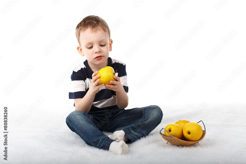 Little cute boy eating a yellow apple and smiling on white backg Little cute boy eating a yellow apple and smiling on white backg