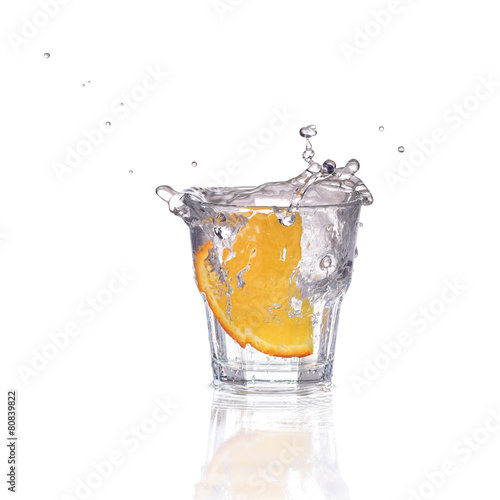 Orange or lemon slice fall in glass with water and make splash