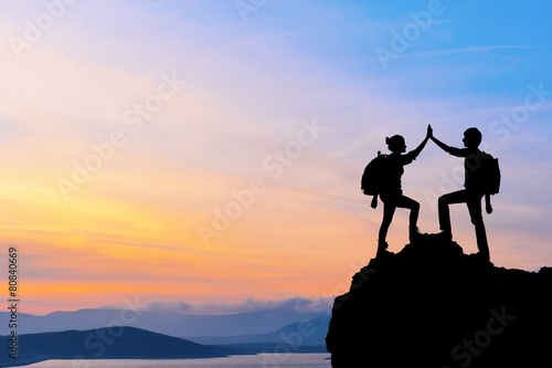 Silhouette of two people man girl success on the mountain