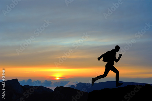 Fototapeta Naklejka Na Ścianę i Meble -  Running jumping man above sunset and mountain. Sport sky