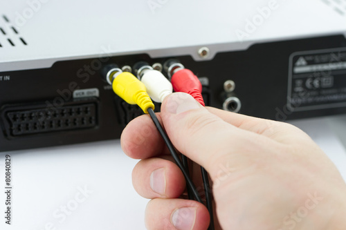 Hand connecting AV cables to AV Receiver