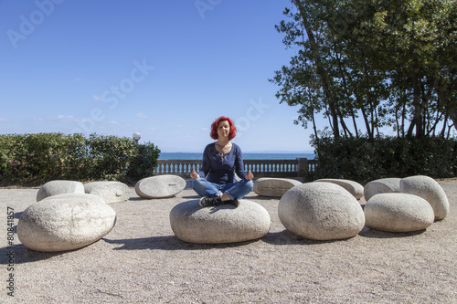 Woman performing joga on energy stones near sea coast