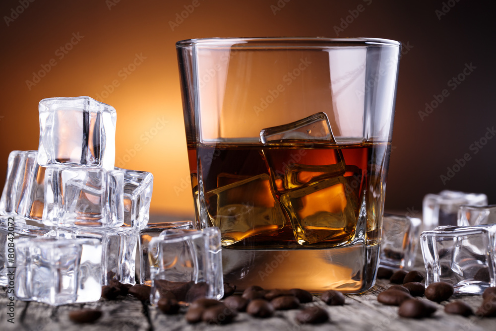 Glass of whiskey with ice and coffee beans.