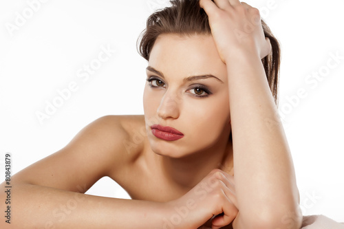 beautiful young woman lying on her hands on a white background