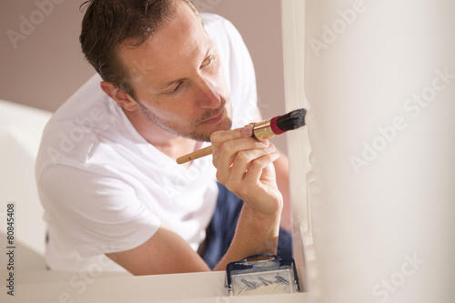 Foto Young male painter painting indoor with paintbrush and white pai