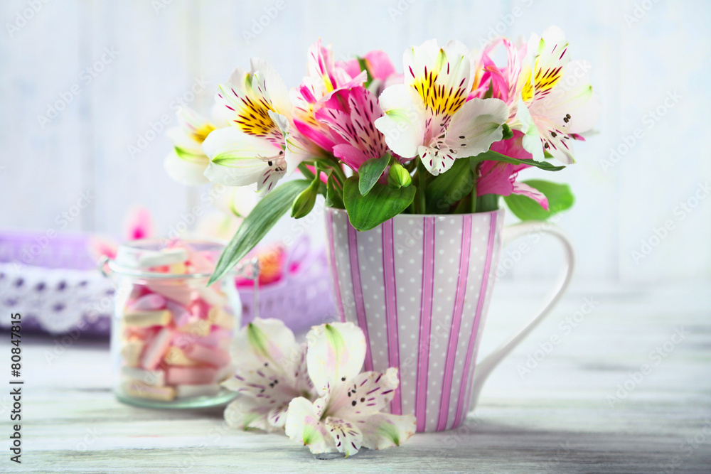 Obraz premium Beautiful flowers in cup, on wooden background
