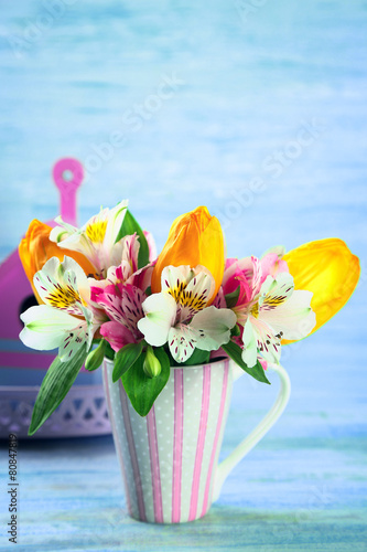 Beautiful flowers in cup, on color wooden background