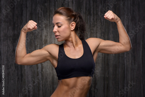 Young mixed race sporty woman demonstrating her biceps
