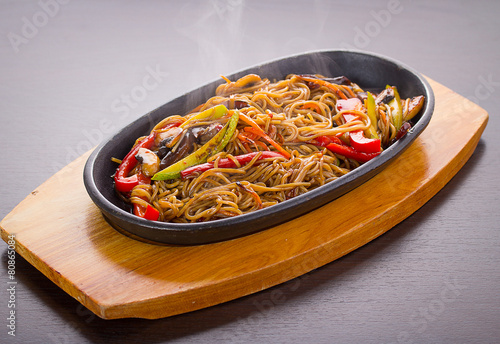 Soba noodles with meal and vegetables over black background