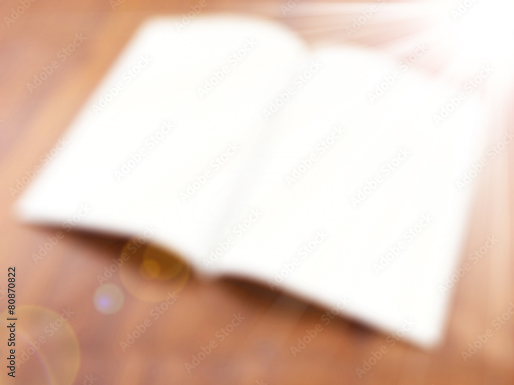 Fototapeta premium Opened magic book on the table,abstract blur background