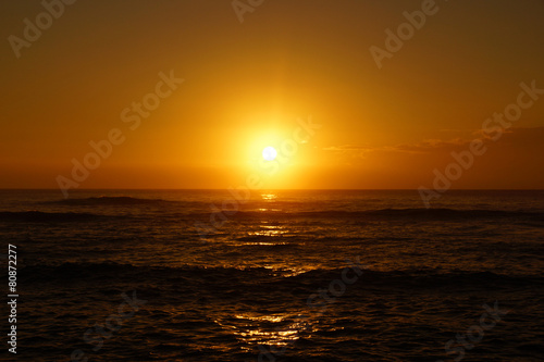 Sunrise over the ocean with waves rolling toward shore