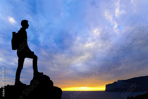 Silhouette of man at the top of the mountain on sunset