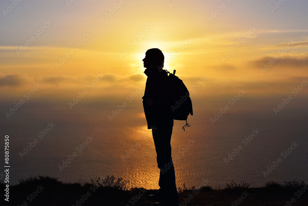 Silhouette of man at the top of the mountain on sunset