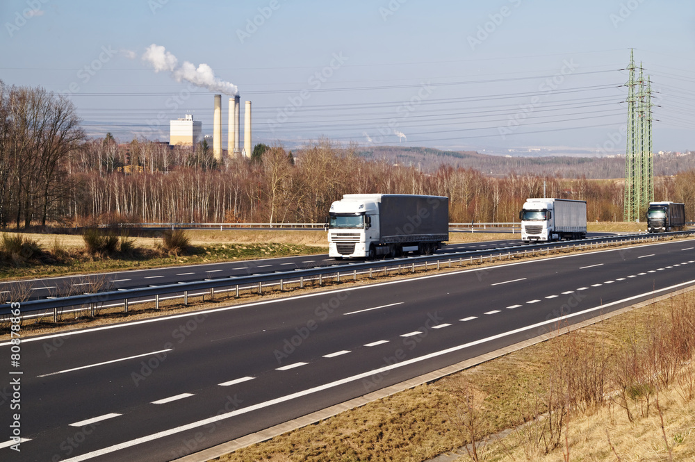 Asphalt highway in the industrial landscape. Three trucks.