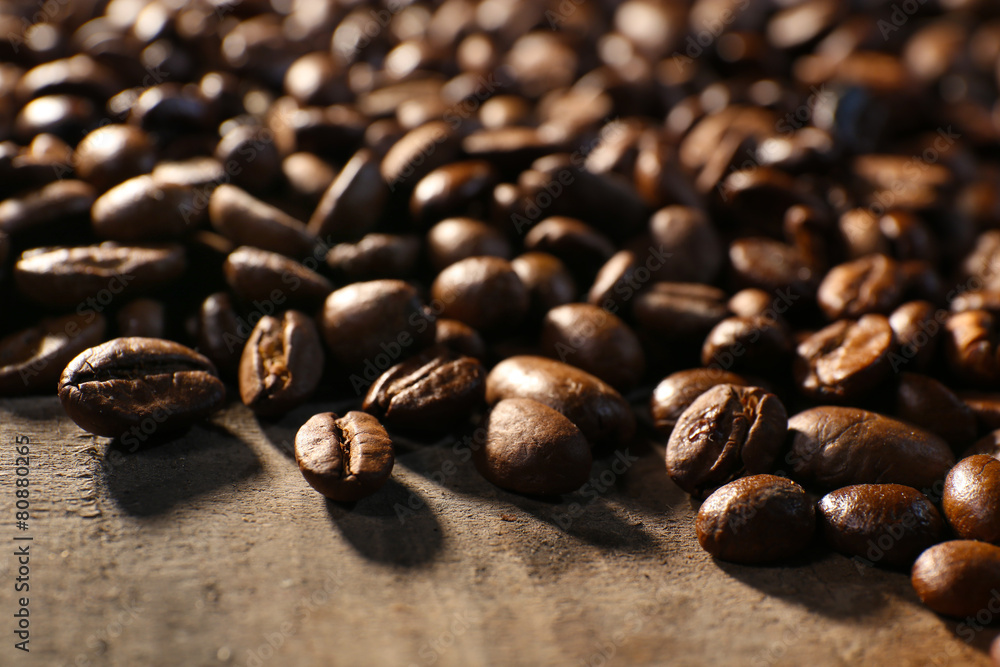 Fototapeta premium Pile of coffee beans on wooden table, closeup
