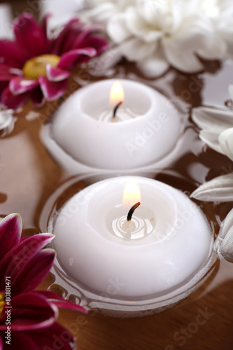 Bowl of spa water with flowers and candles  closeup