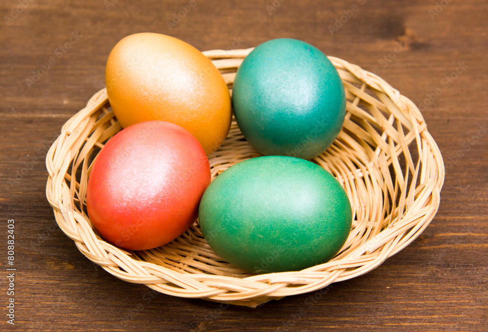 Basket with colored eggs on wooden table Basket with colored eggs on wooden table