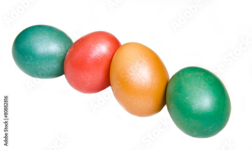 Oblique row of colored eggs on white background