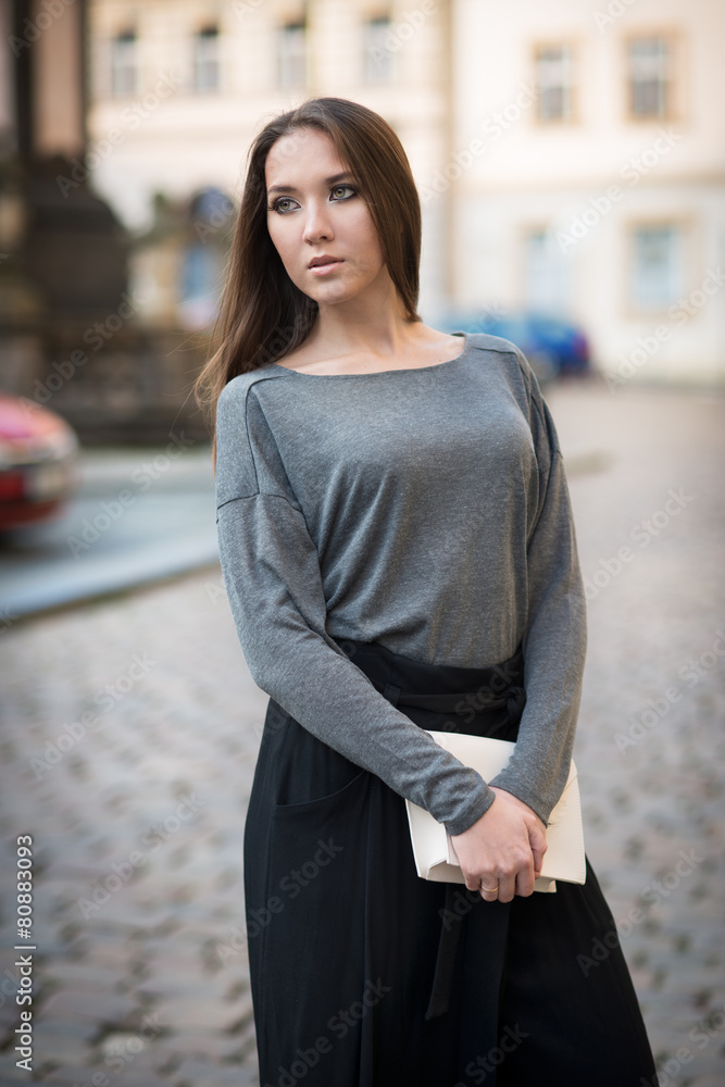 Elegant woman in the city holding white clutch
