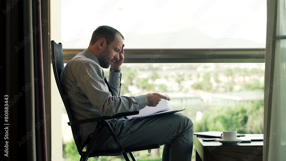 Sad, overwhelmed, businessman working with documents sitting on Sad, overwhelmed, businessman working with documents sitting on