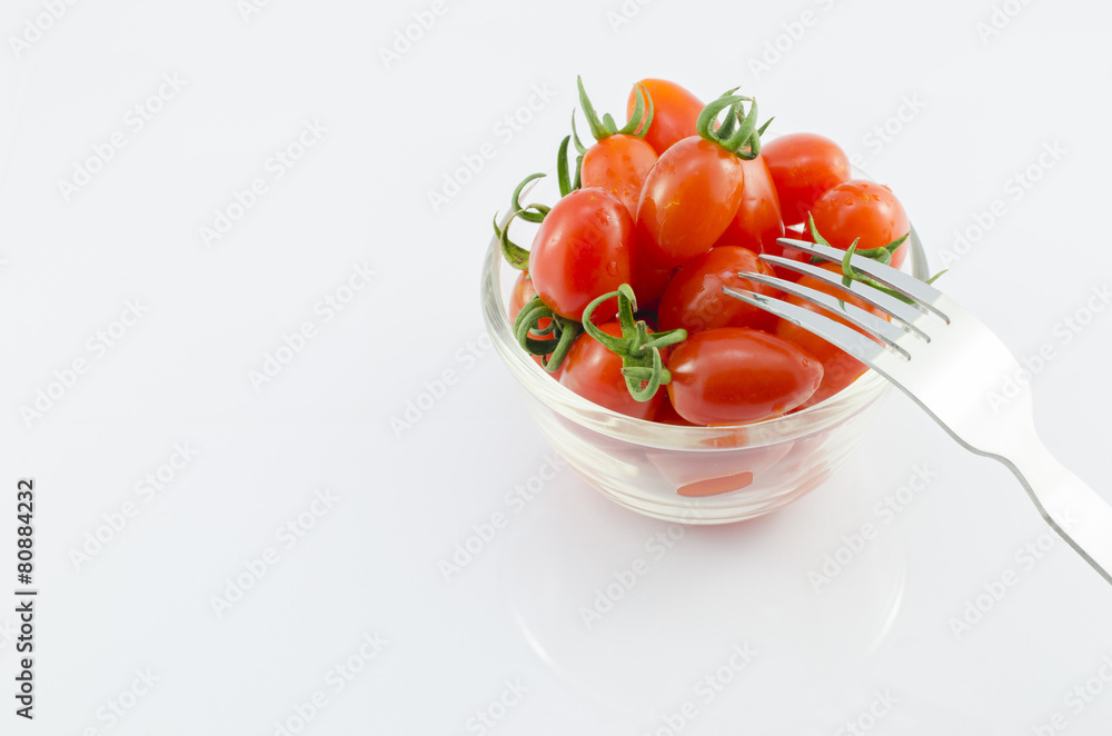 Red Cherry Tomatoes in bowl with fork on white background Red Cherry Tomatoes in bowl with fork on white background