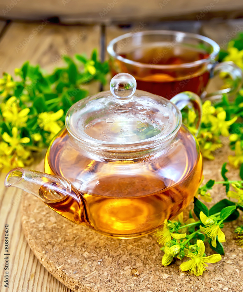 Tea from tutsan in glass teapot and cup on board Tea from tutsan in glass teapot and cup on board