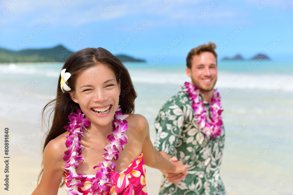 Happy Hawaii beach holiday couple in Hawaiian leis