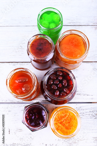 Homemade jars of fruits jam on color wooden planks background