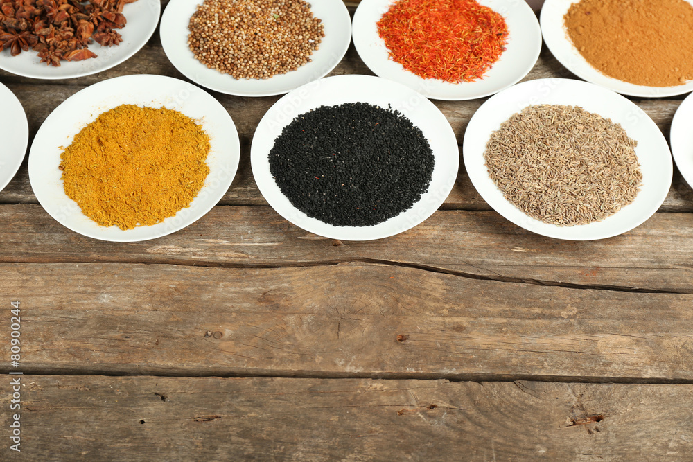 Different spices on plates, on old wooden table