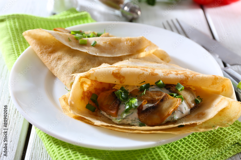 Pancakes with creamy mushrooms and greens in plate