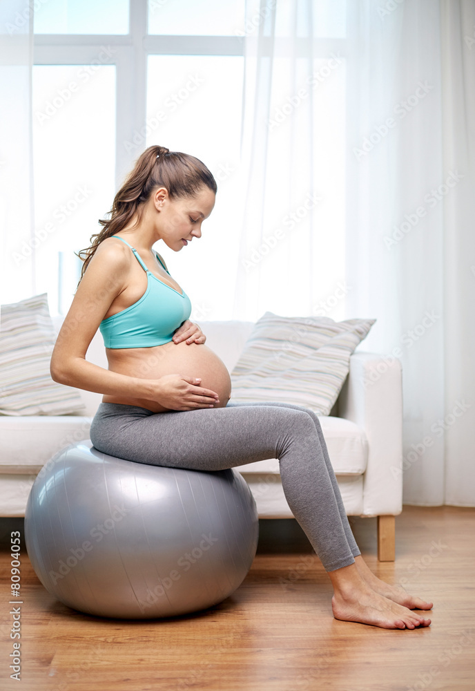 happy pregnant woman exercising on fitball at home