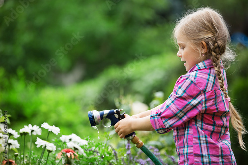 Mädchen spielt mit Gartenschlauch