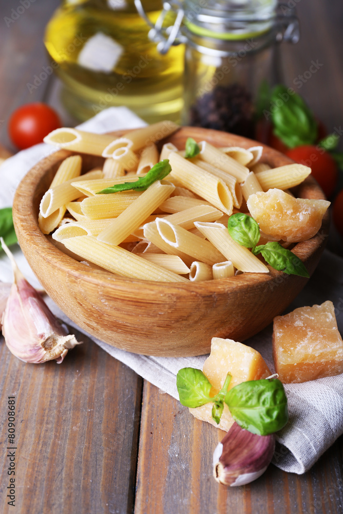 Raw pasta in bowl with cheese and vegetables on table close up Raw pasta in bowl with cheese and vegetables on table close up