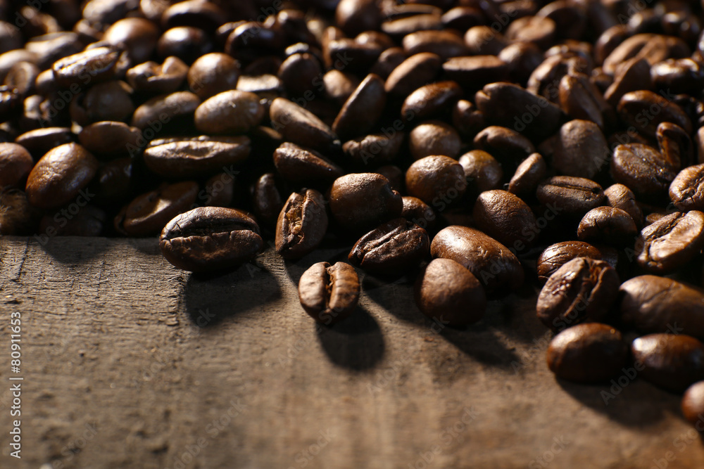 Fototapeta premium Pile of coffee beans on wooden table, closeup