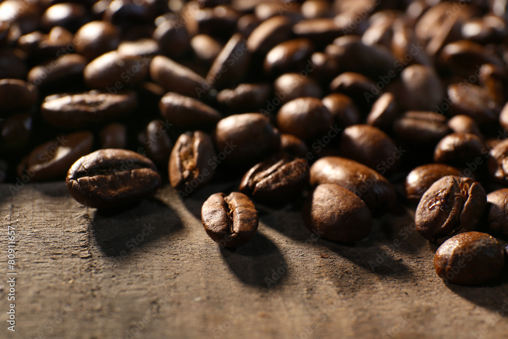 Fototapeta premium Pile of coffee beans on wooden table, closeup