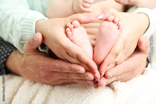 Newborn baby feet on father and mother hands, close-up